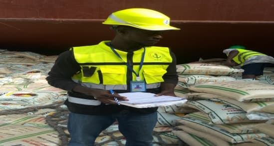 PGS surveyor in high-visibility gear conducting a cargo inspection on rice bags